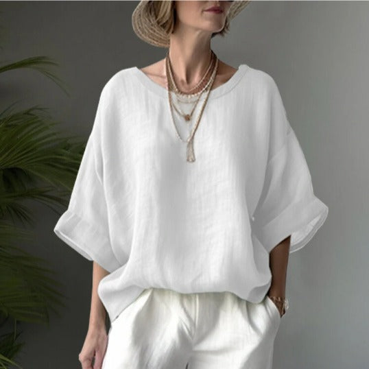 Person wearing a white blouse and white pants against a gray background