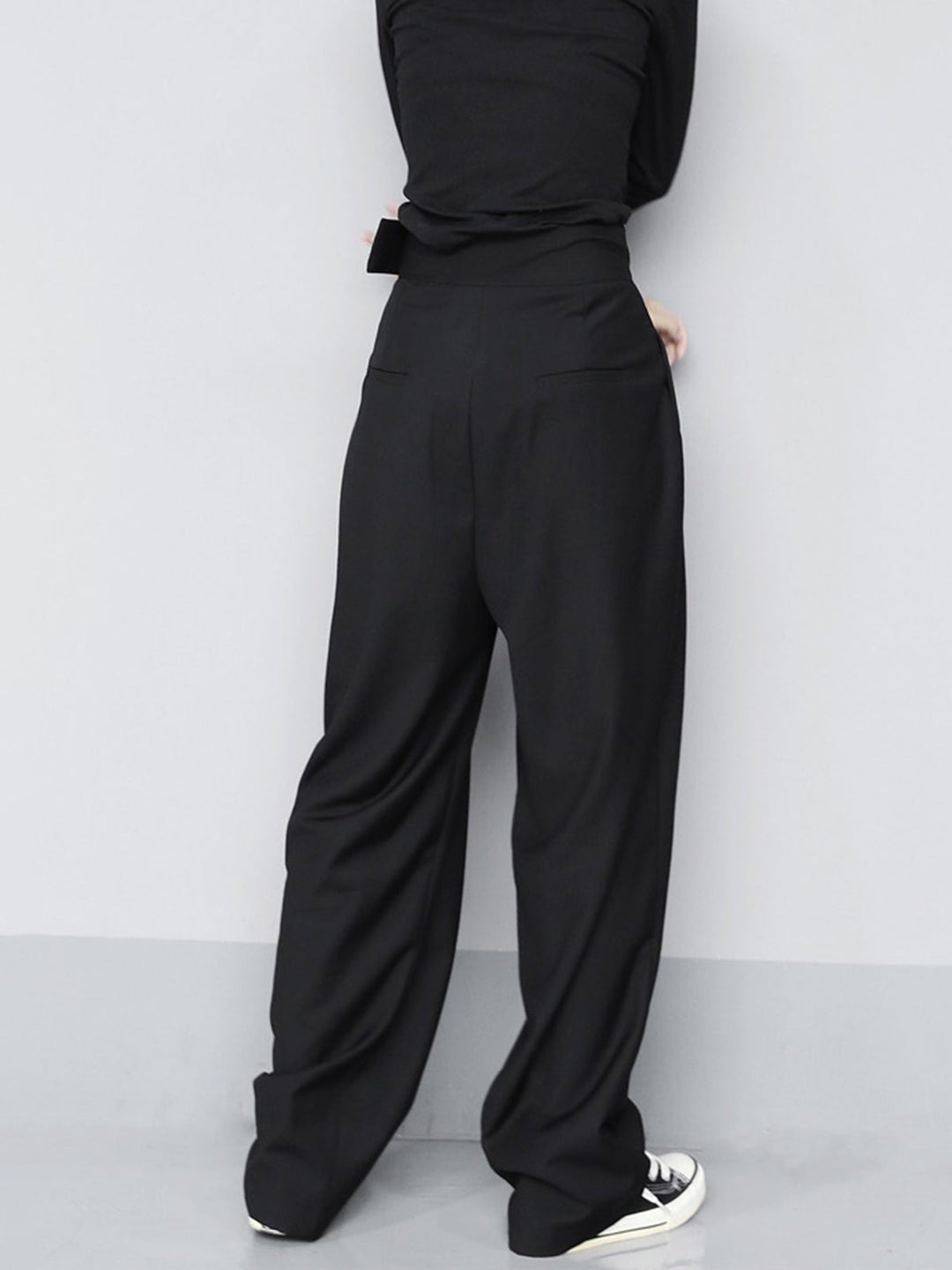 Person wearing black high-waisted pants against a white background