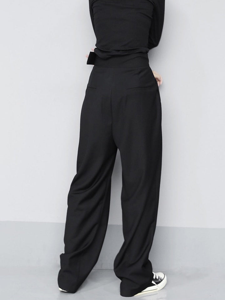 Person wearing black high-waisted pants against a white background