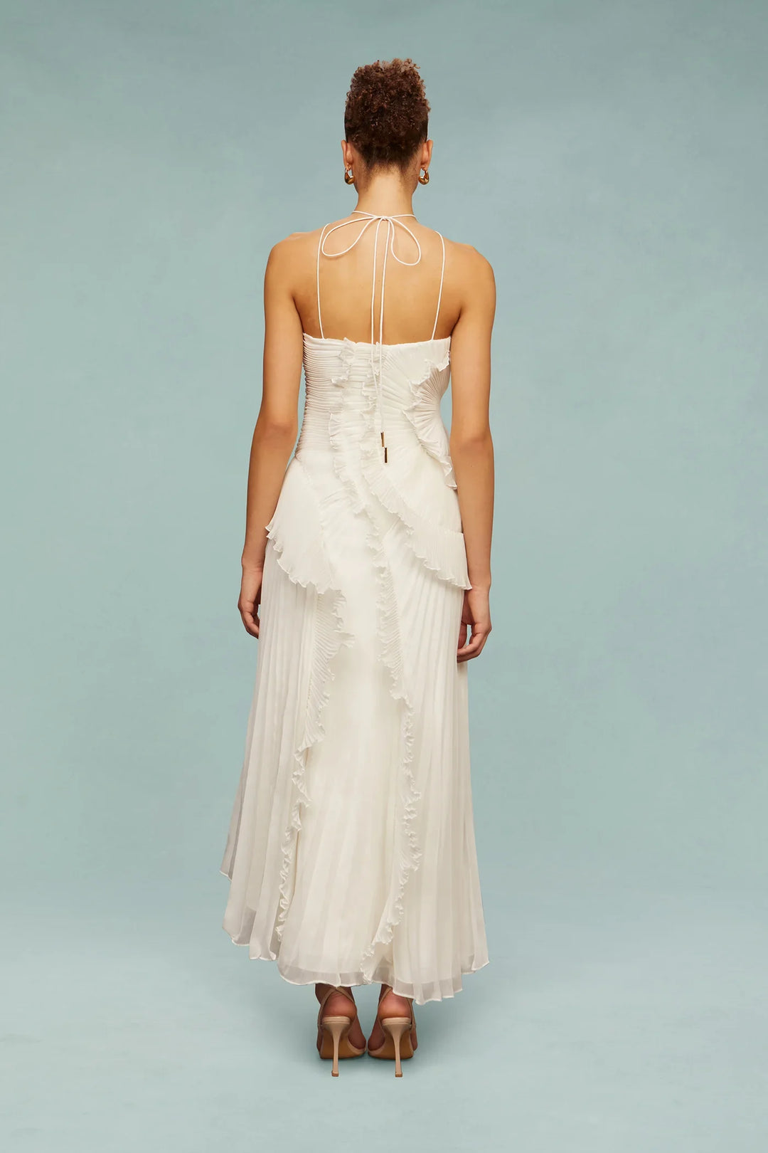 Woman wearing a white dress with thin straps on a light blue background