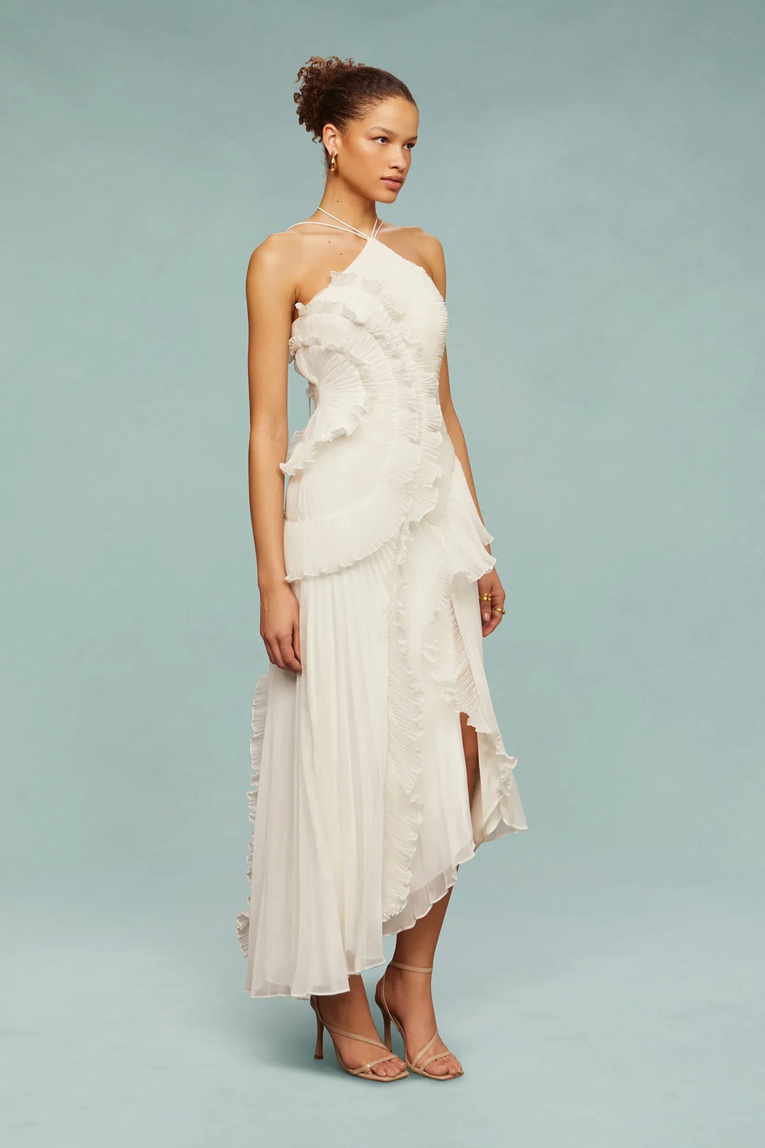 Woman wearing a white strapless dress with ruffled layers on a light gray background