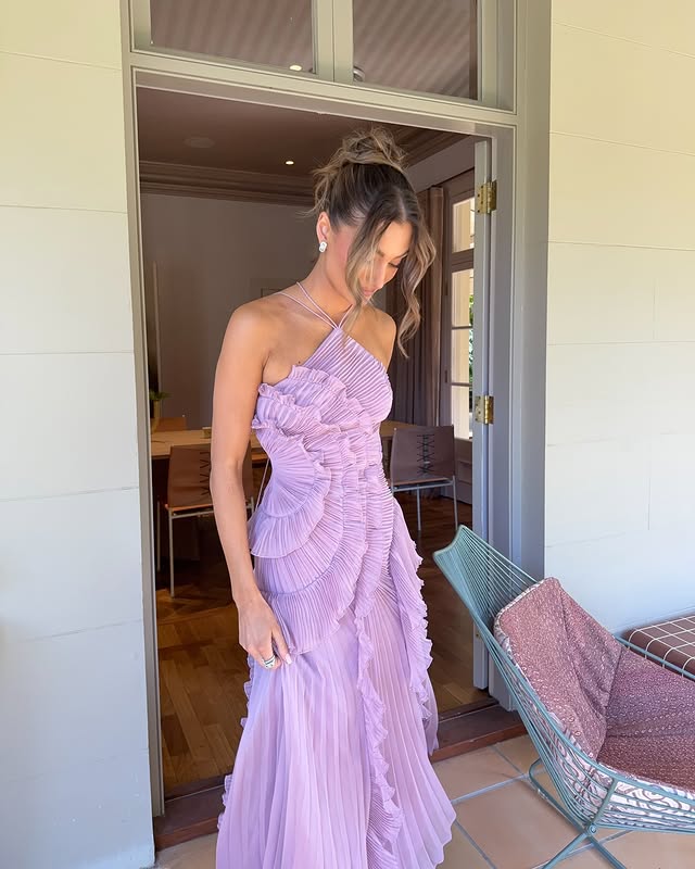 Woman in a lavender dress standing in a doorway.