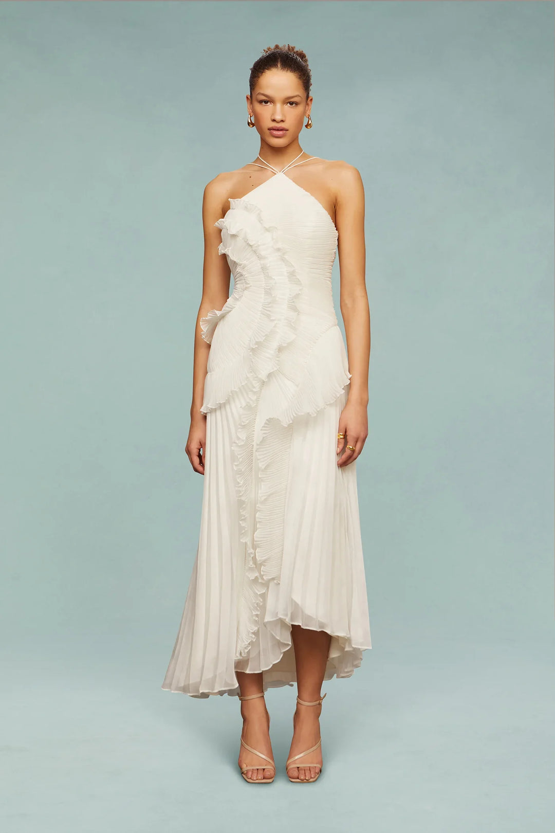 Woman wearing a white halter-neck dress with floral details on a light blue background