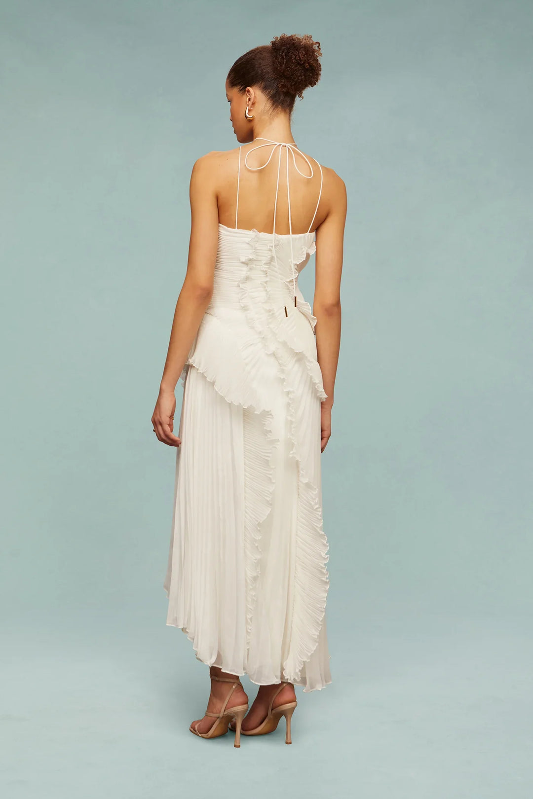 Woman wearing a white dress with thin straps on a light blue background