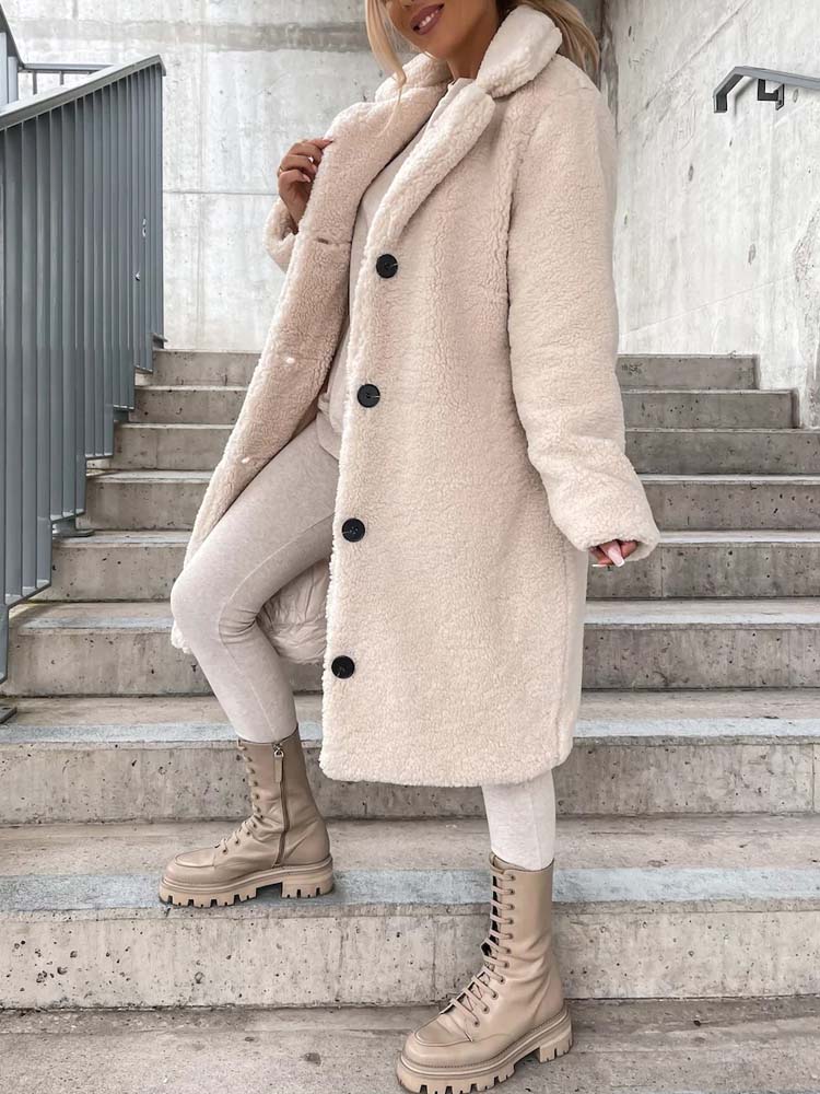 Person wearing a long beige coat with black buttons on a set of stairs.