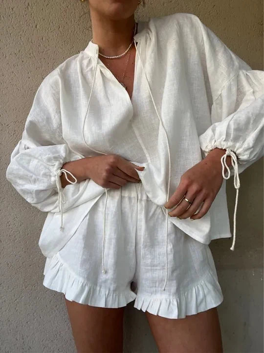 Person wearing a white outfit with ruffled shorts against a plain background