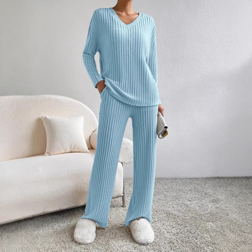 Person wearing a light blue ribbed pajama set with white slippers in a room with a beige sofa.