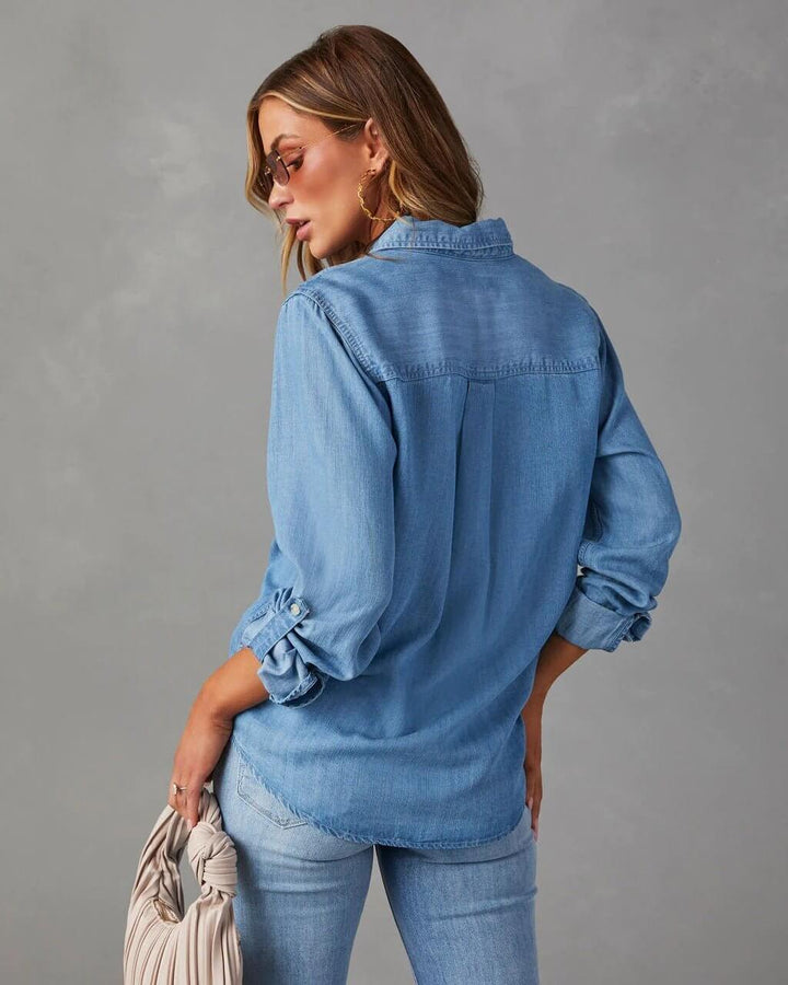 Woman wearing a blue denim shirt and jeans against a gray background