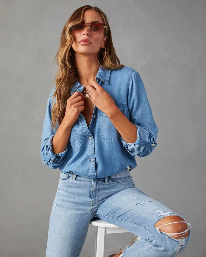 Woman in denim shirt and jeans posing against a gray background