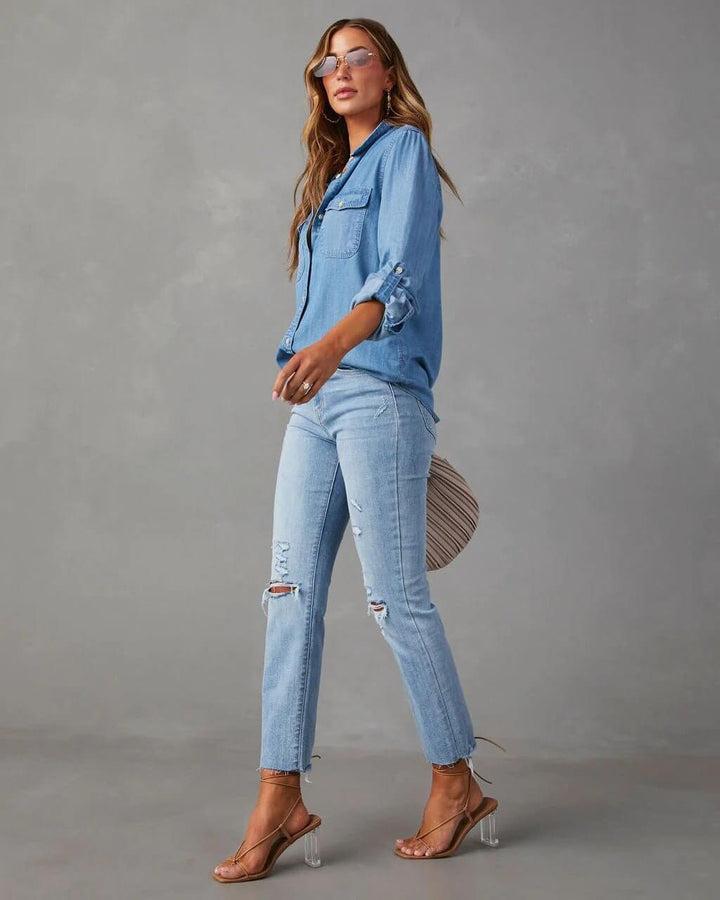 Woman in denim outfit with clear heels on a gray background
